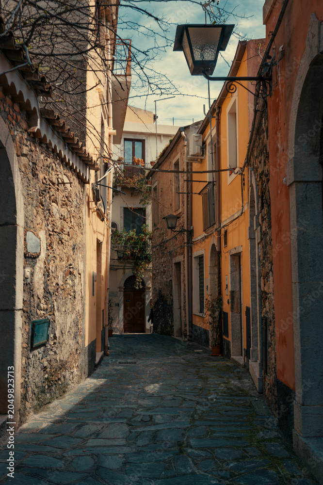 Fototapeta premium Narrow Alleyway with Old Stone Walls and Historic Buildings in Taormina