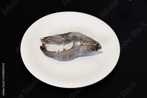 Cooked shrimp served on a white plate. Shrimp cooking in boiling water. Raw shrimp on a white plate