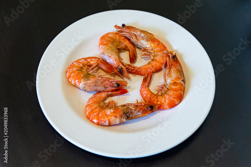 Cooked shrimp served on a white plate. Shrimp cooking in boiling water. Raw shrimp on a white plate