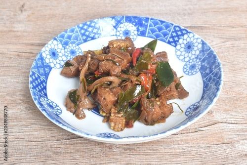spicy fried fat pork belly with vegetable and lemon leaf in shrimp paste sauce on plate