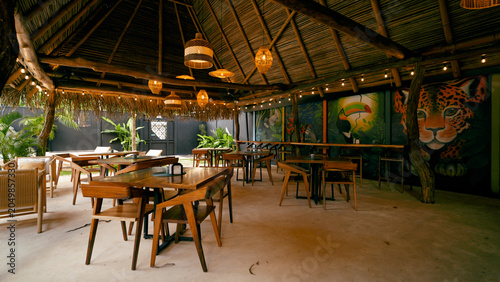 Принти на полотні Open air restaurant under a thatched palapa roof, featuring wooden tables, woven