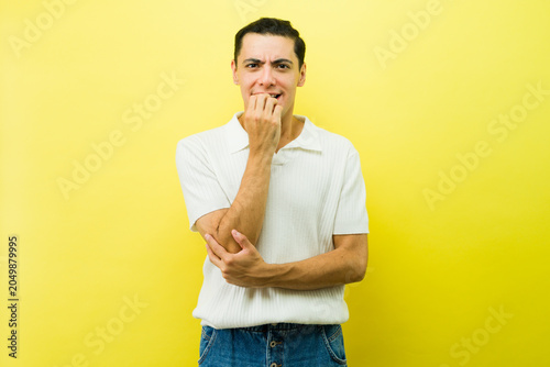 Canvas-taulu Stressed young man biting nails, feeling anxious, showing worry and nervousness