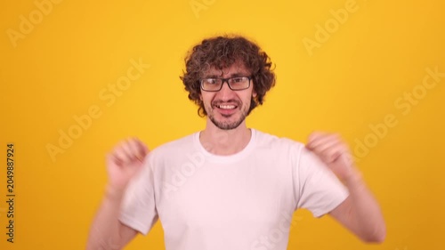 Sincere joyful man raising hands with lively motion and bright yellow backdrop conveying positive emotion, confidence and energetic winner attitude for strong commercial lifestyle themes