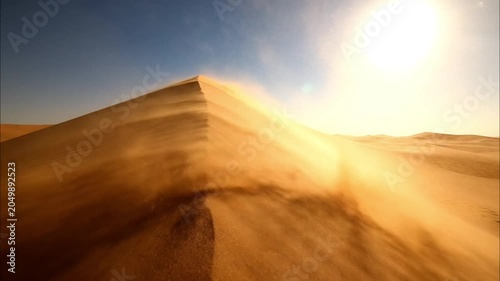 Golden sand dunes landscape in desert under bright sky with motion blur effect
