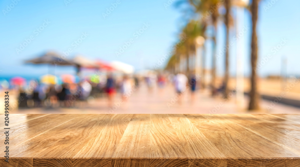 Fototapeta premium Empty Wooden Table Top with Blurred Beach Promenade Background for Summer Product Presentation and Travel Mockup.