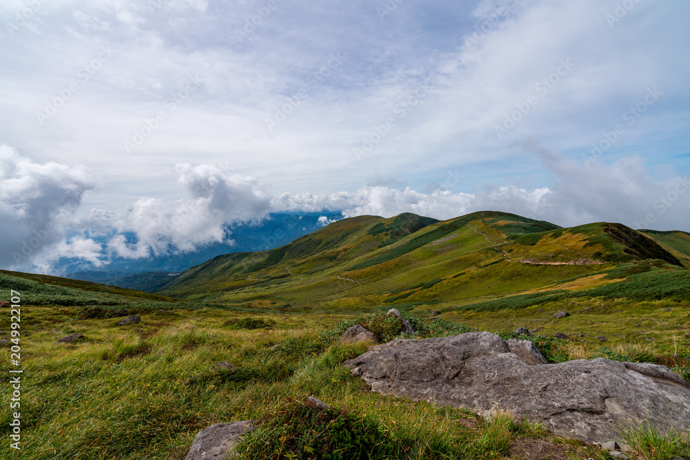Fototapeta premium 岩肌と草原が広がる月山の美しい稜線と登山道の風景