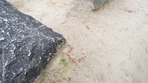 Large stone blocks resting on sandy ground in outdoor setting. Natural rock formations, textured stone surfaces, landscape design elements, minimalist nature scene, and outdoor photography concept.
