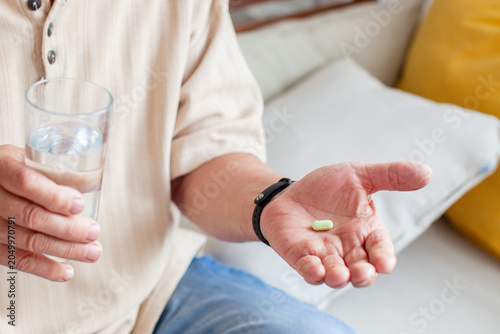Obraz na płótnie Man holding a pill and a glass of water before taking medication