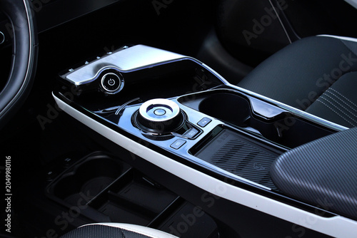 Close-up of an automotive center tunnel showcasing a rotary gear controller, storage compartments, and refined interior styling in modern electric vehicle.