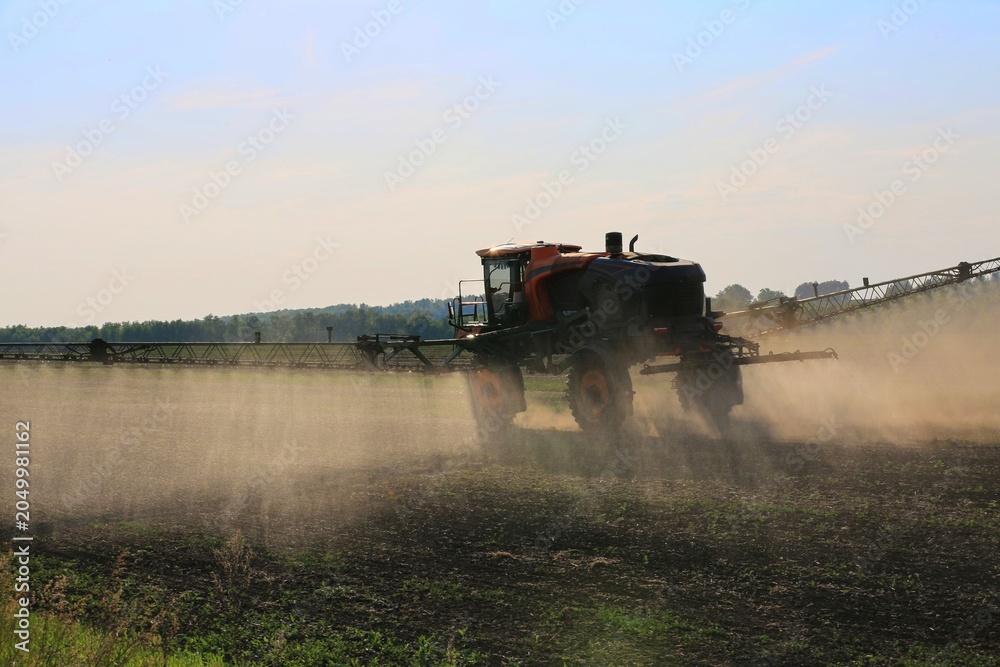 Naklejka premium agricultural machinery fertilizes a farm field with crops