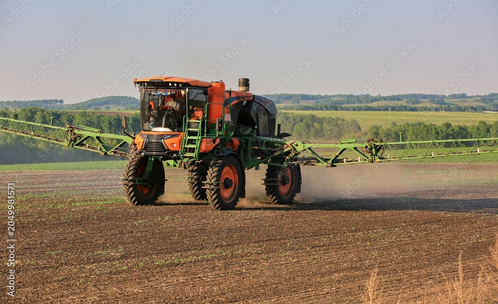 Obraz premium agricultural machinery fertilizes a farm field with crops
