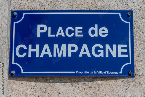 Epernay, France, May 23, 2026.  A traditional French blue enamel street sign reading ' PLACE de CHAMPAGNE' on a textured stone wall.
