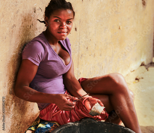 Young Cameroonian woman cleaning and preparing fresh fish in front of her home in a rural village near the Atlantic coast of Cameroon.
