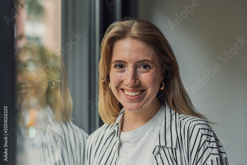 Canvastavla Young happy woman with blonde hair and a striped shirt smiling brightly at the c