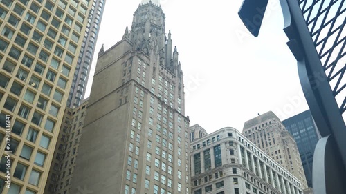 A modern abstract sculpture stands in front of historic and contemporary buildings in a city center. The architectural scene highlights contrast between classic design and modern urban development.