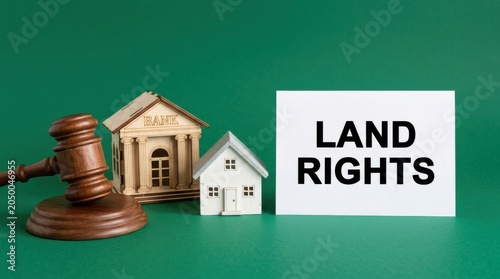 Land rights concept with judge gavel and house model, real estate law and property ownership symbols, legal bank building on green background