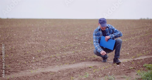 Man inspecting plowed soil in rural field
