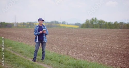 Man checking a mobile device beside a rural field