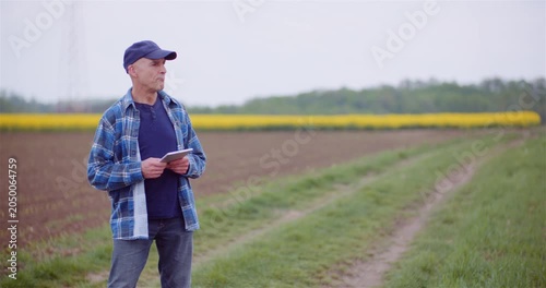 Man standing in a rural field holding a tablet