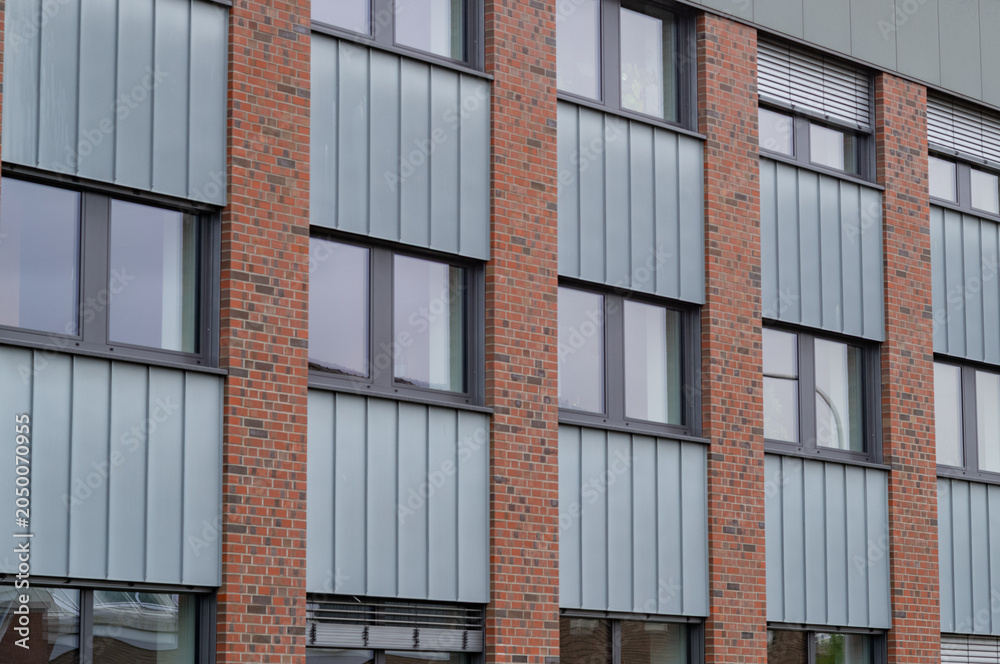 Obraz premium Modern building design with brick and metal panels in urban setting captured during daylight hours