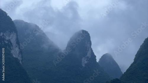 Timelapse showing the movement of heavy white mist and foggy clouds swirling around the towering karst mountain peaks in the scenic landscape of Guilin, Guilin, China. Atmospheric weather and nature 