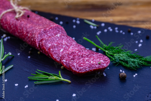 Sliced dry smoked salami sausage on a slate board