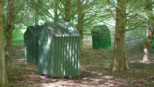 Tableau sur toile Small green metal sheds tucked away in a shady woodland grove