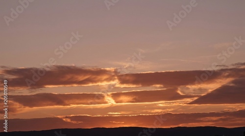 Experience the serene beauty of twilight as a breathtaking Atmospheric Sunset Sky Background paints the horizon with warm hues and structured clouds