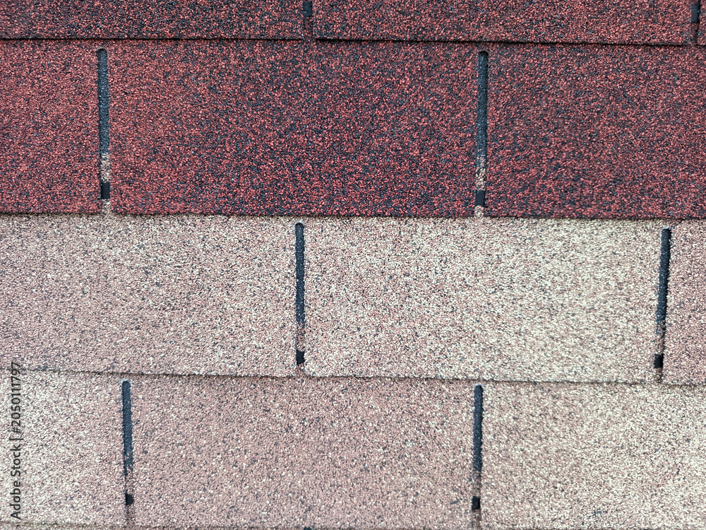 Fototapeta premium Detailed top-down view of overlapping asphalt roof shingles featuring a gritty, mineral-granule texture in various shades