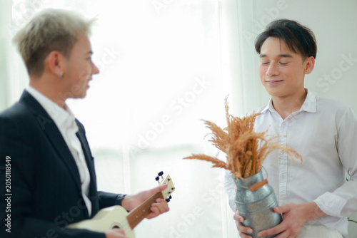 Cuadro en lienzo Gay male couple uses persuasive language and flirting impress and capture the other's attention during intimate activities at home such as playing the ukulele showcase their talents