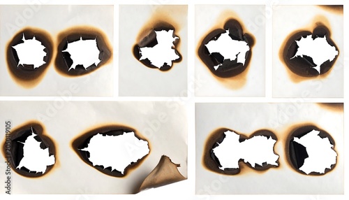 Isolated close-up shot of multiple pieces of off-white paper with various irregular holes created by charring