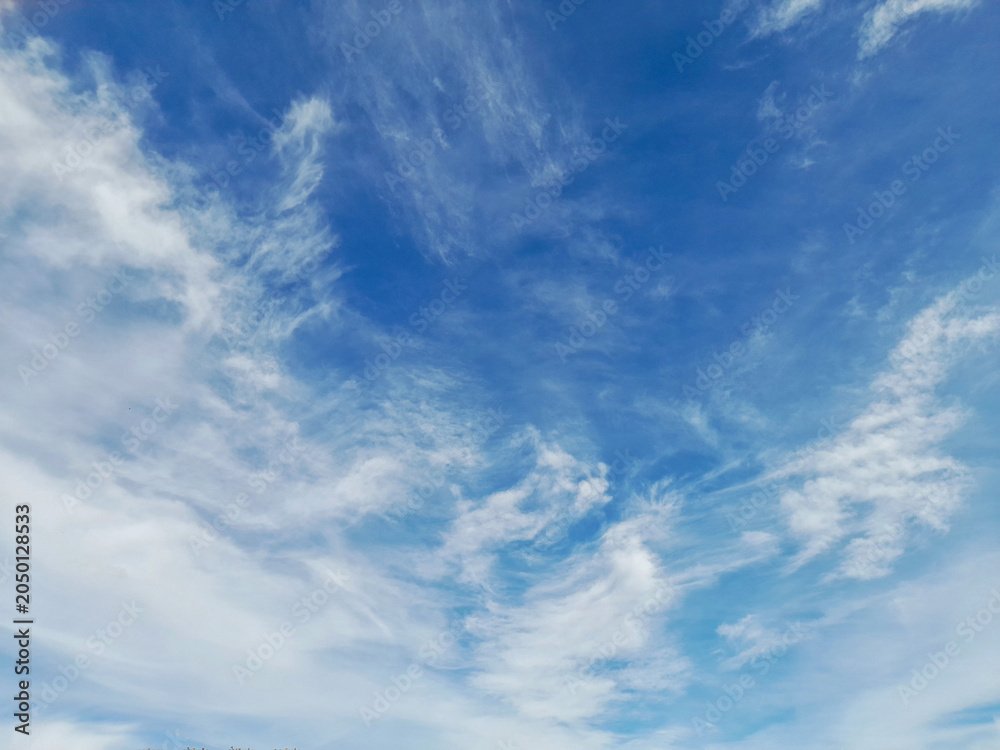 Obraz premium Beautiful wispy clouds scattered across a bright blue summer sky.