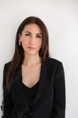 Bild auf Leinwand Caucasian woman looking at camera in black formal pantsuit stands against white background