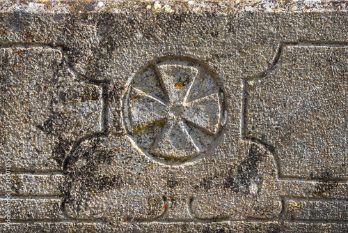 Weathered stone carves a central cross emblem