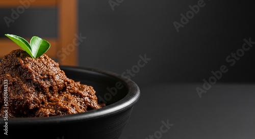 Beef Rendang dish served in earthenware bowl on table indoors.