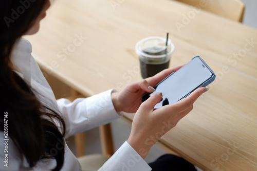 Businesswoman Using Smartphone While Drinking Iced Coffee In A Modern Cafe During Work Break