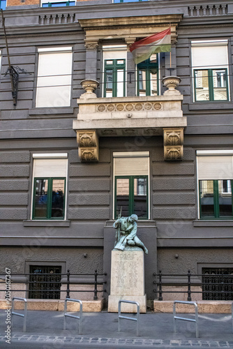 Facade of an ancient house in Budapest, Hungary, with a statue in front of the house