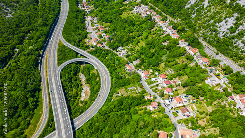 Φωτογραφία Drone shot of a major highway intersection cutting through verdant Croatian landscape, with a charming village nestled in the hills
