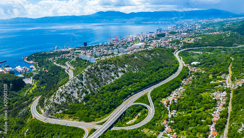 Foto Aerial view of Rijeka, Croatia, showcasing its vibrant port, sprawling city, and intricate highway nestled between lush hills and the sparkling Adriatic Sea