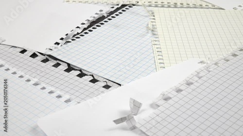 Sheets torn from various spring-bound notebooks lie on a table, background