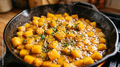 Roasted butternut squash cubes in a cast iron skillet with herbs