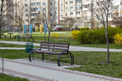 Rest area with bench surrounded by trees and ornamental shrubs in Kyiv, Europe. Place to rest in the city at spring