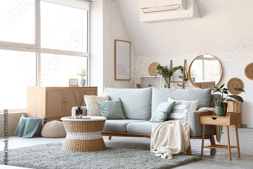 Foto Interior of living room with sofa, wicker coffee table, houseplants and commode