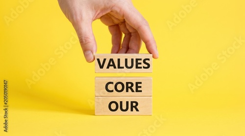 Hand holding wooden blocks with core values text on yellow background