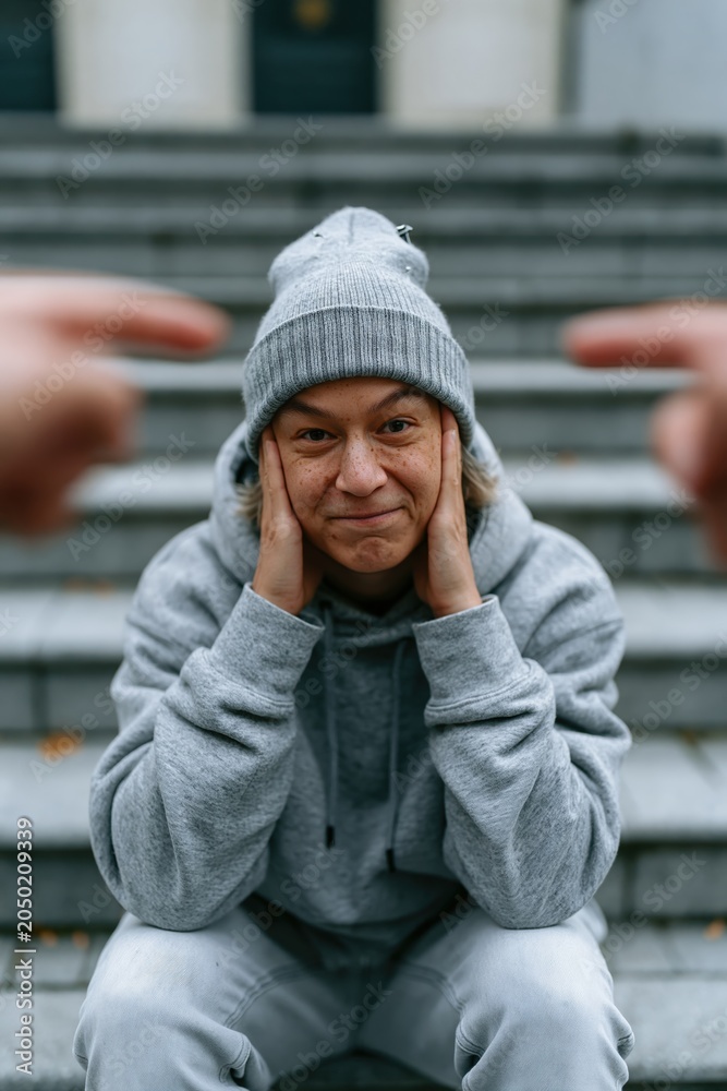 Fototapeta premium Person sitting alone covering ears while being blamed on urban steps