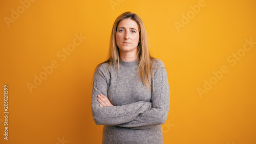 Canvas Print Confident woman with a serious face standing against a yellow background, lookin