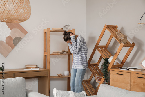 Scared young woman in livin...