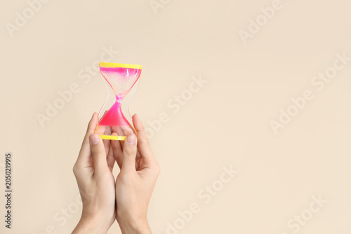 Foto Female hands holding hourglass on beige background