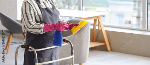 Mature woman with walker spraying detergent on rag at home