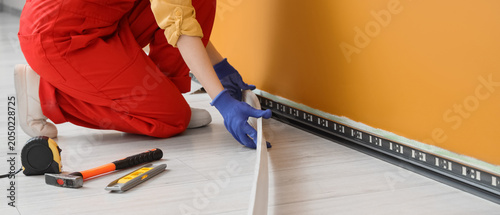 Photos Worker installing laminate flooring with underlay near orange wall during home r